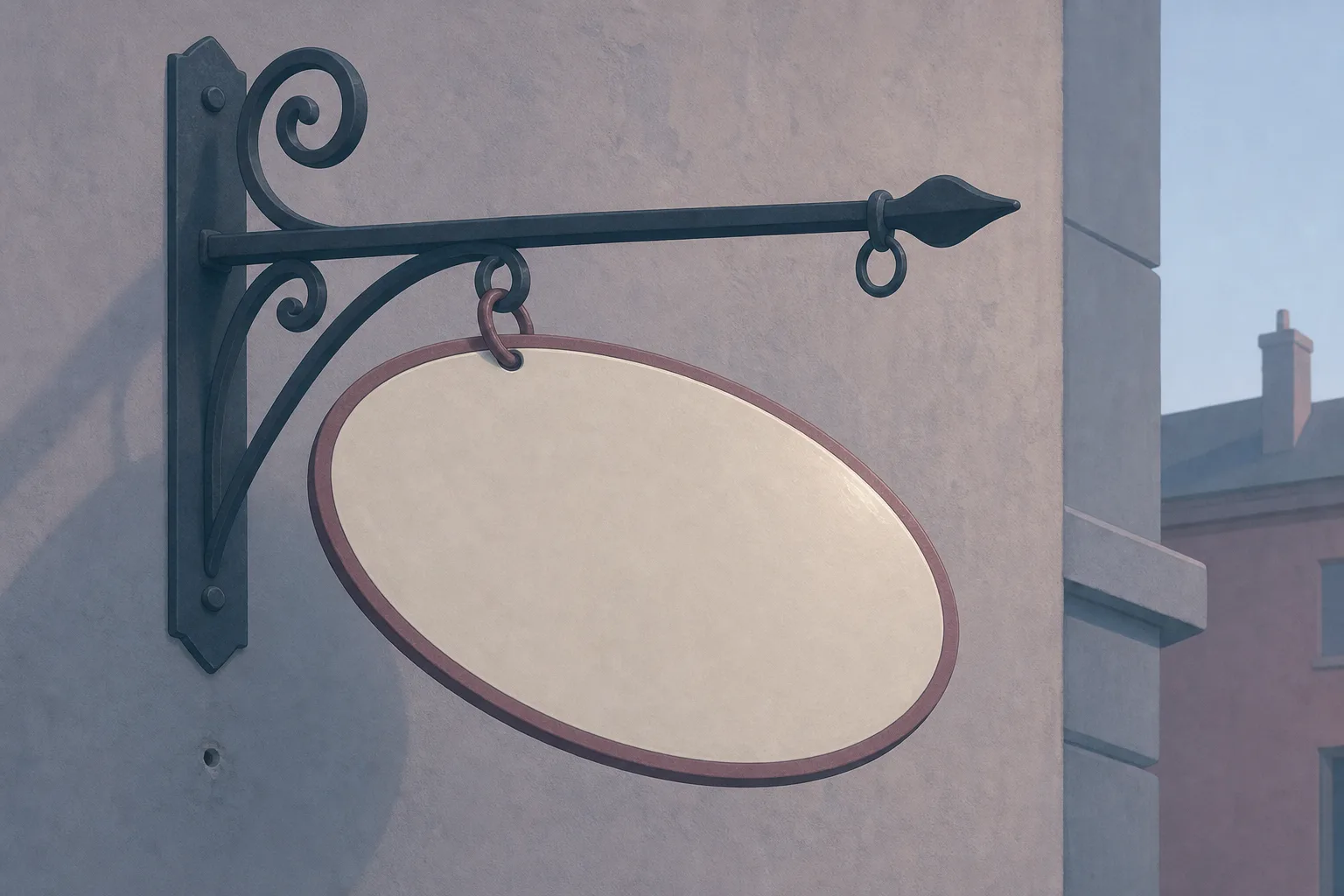 A blank unmarked enamel shop sign hanging from an iron bracket by one remaining ring, the second ring empty beside it, against a plain wall in dusty rose and slate.